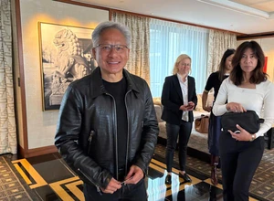 На фоне интерьера с картинами группа людей, один мужчина с улыбкой в кожаной куртке.