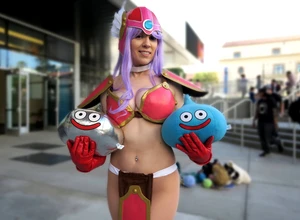 Женщина в костюме с фиолетовыми волосами, держащая игрушки с улыбающимися лицами.