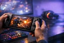 Рука держит портативную игровую консоль с активной игрой на экране.