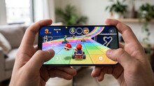 На смартфоне играют в гонки на яркой трассе, управляя персонажем в картинге.