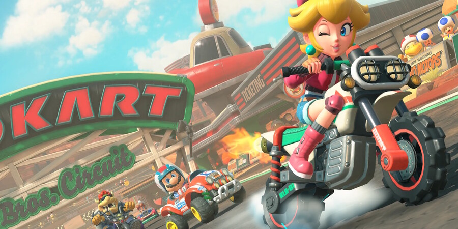 Персонаж в розовом костюме едет на мотоцикле по трассе с другими гонщиками.