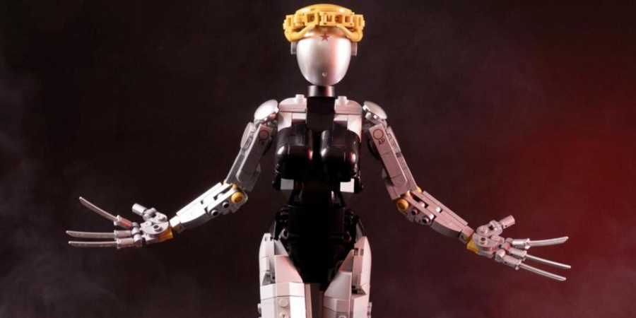 Робот с короной на голове, поднимающий руки, на фоне дымного темного окружения.